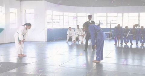 Bowing judo competitors before match wearing white and blue gis with green and black belts