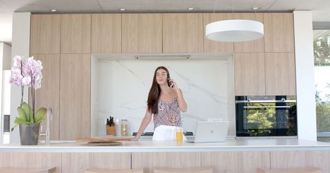 Teenage Girl Chatting on Phone in Modern Kitchen Setting