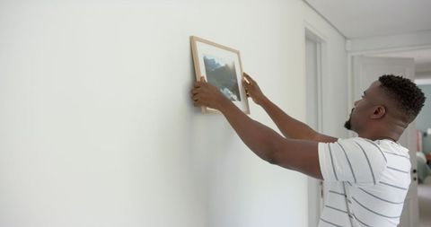 Man Hanging Framed Photograph on White Wall at Home - Download Free Stock Images Pikwizard.com