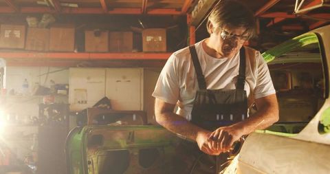 Mechanic precision grinding car in workshop with goggles