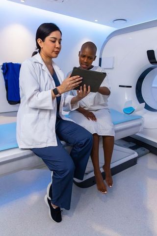 African american clinician reviewing tablet with patient before ct scan in radiology suite