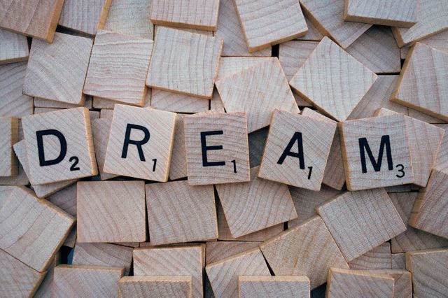 Wooden blocks with individual letters spelling the word 'dream'. Ideal for use in content about creativity, motivation, inspiration, personal goals, and the power of dreaming. Perfect for blog posts, articles, presentations, and educational materials.