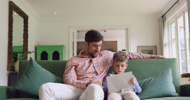 Father and Son Using Digital Tablet on Green Couch in Living Room - Download Free Stock Images Pikwizard.com