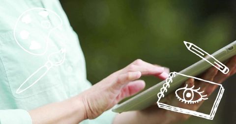 Mature woman holding tablet tapping screen outdoors with creative doodles