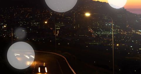 Curving Highway Long Exposure Car Light Trails Overlook with City Skyline Bokeh Lens Flare