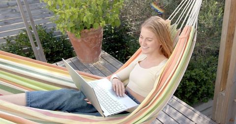 Woman Relaxing in Hammock Using Laptop Outdoors