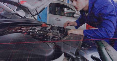 Mechanic inspecting engine wiring in garage workshop wearing blue coverall diagnosing vehicle