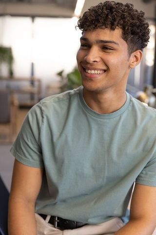 Smiling Young Man Sitting in Modern Coworking Space