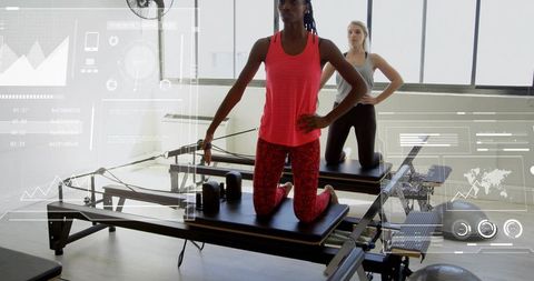Two women practicing Pilates on reformers with digital fitness HUD overlays in studio