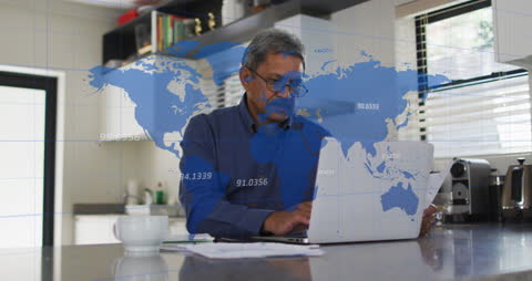 Senior Man Analyzing Global Data on Laptop in Modern Kitchen