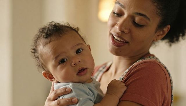 Mother holding infant close singing soothing lullaby at home tender new parent bonding