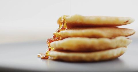 Stacked pancakes dripping amber maple syrup minimalist close-up