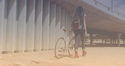 Young Man with Bicycle Walking Under Bridge