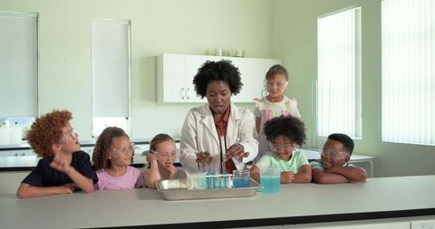 African american teacher leading hands-on science experiment with elementary students in school lab