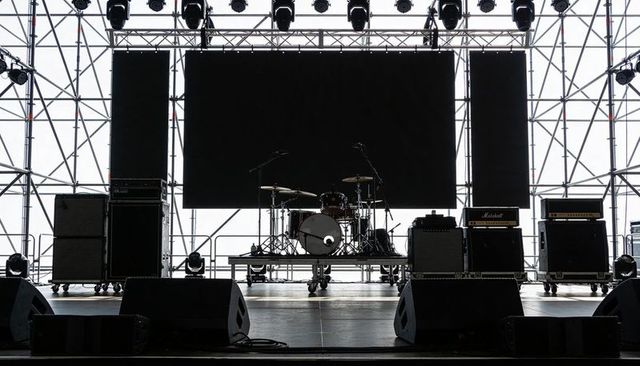 Empty outdoor concert stage with drum kit and amplifier stacks during soundcheck