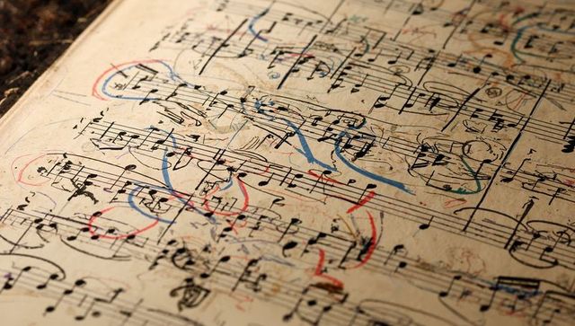 Aged musical score showing color-coded annotations, pen and pencil marks on manuscript