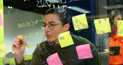 Woman engineering business ideas on glass wall with digital network overlay