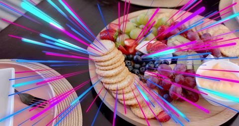 Vibrant neon charcuterie board featuring crackers, grapes, strawberries and dip