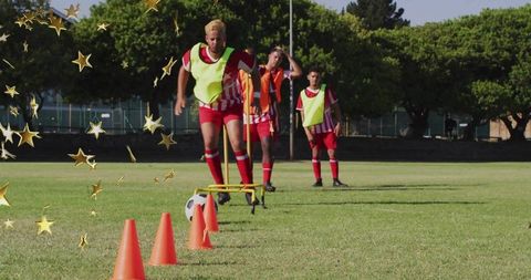 Youth soccer team practicing agility drill with cones and hurdles on sunny grass pitch