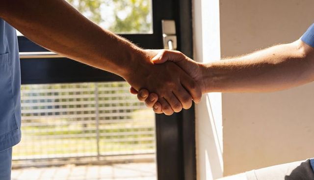 Healthcare workers shaking hands in clinic doorway sunlit greeting conveying trust