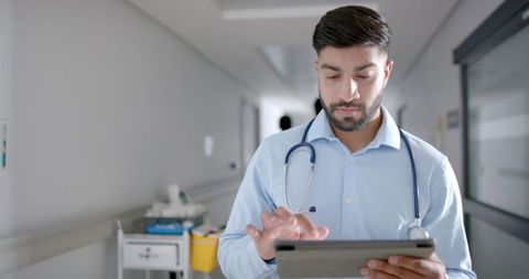 Focused Doctor Reviewing Patient Data on a Tablet in Hospital