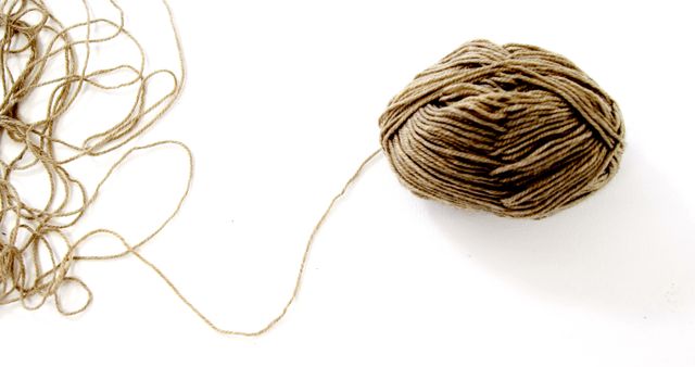 A ball of yarn is neatly wound next to a tangle of loose threads, with copy space. The contrast between the organized yarn and the messy strands could represent concepts of order and chaos.