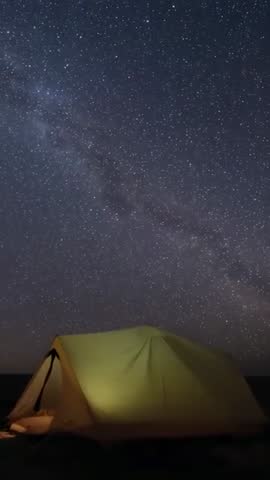 Capturing glowing yellow-green tent under Milky Way on starry night vertical video