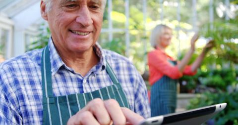 Mature Gardener Using Digital Tablet in Greenhouse