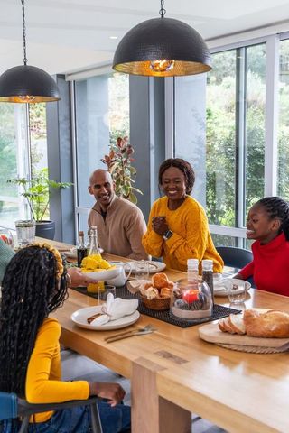 African american family sharing joyful home dinner around modern wooden table in sunlight