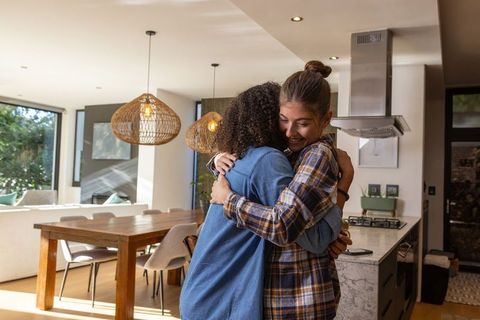 Joyful Friends Hugging in Cozy Modern Kitchen Interior