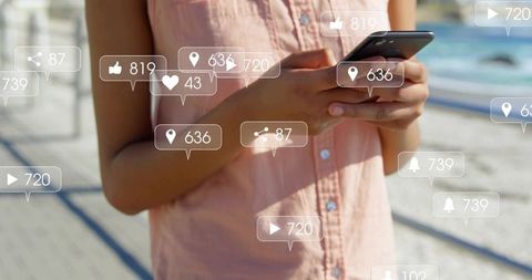 Adult woman tapping smartphone on sunlit pier with floating social media notifications