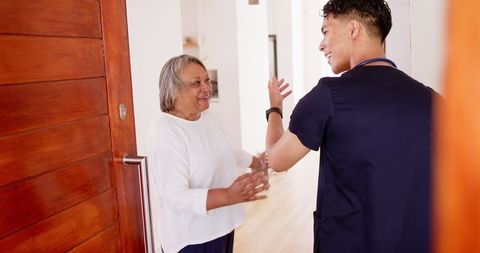 Senior woman welcoming visitor home, smiling and supporting community