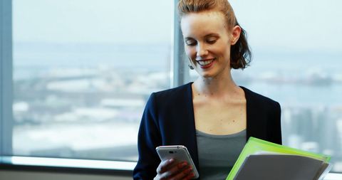 Smiling Businesswoman Checking Mobile Phone Holding Folders - Download Free Stock Images Pikwizard.com