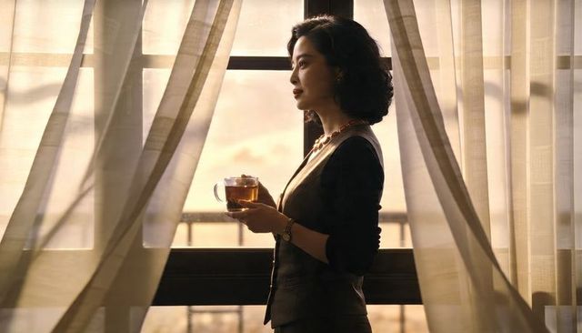 Executive woman standing at highrise window holding tea, gazing at skyline in golden hour