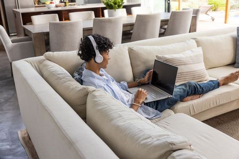 Relaxed Man Using Laptop on Sofa with Headphones in Modern Home