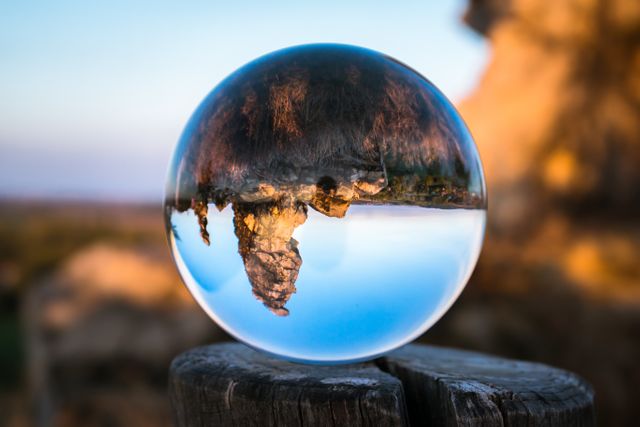 Crystal sphere reflecting mountainous landscape with sunrise lighting creates surreal and tranquil scene. Perfect for concepts of reflection, nature's beauty, and alternative perspectives in photography compositions, promotional materials, or environmental storytelling.