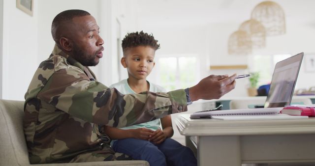 African american father with son learning together with laptop. Spending quality time together, army and patriotism concept.