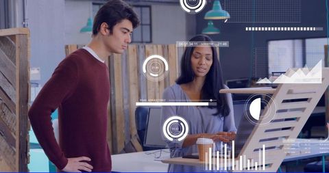 Young professionals collaborating over laptop at standing desk with data overlays