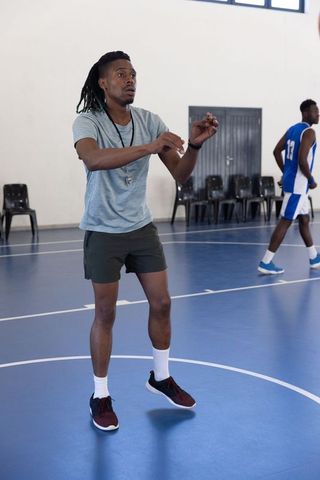 Basketball coach guiding player on indoor court