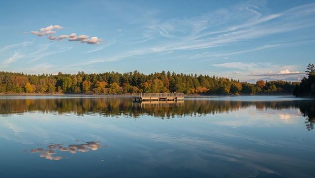 Sunlit Floating Dock Reflecting Autumn Forest on Mirror-Calm Lake at Golden Hour