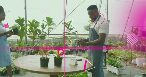 Greenhouse staff checking phone while watering plants in urban nursery with pink overlays