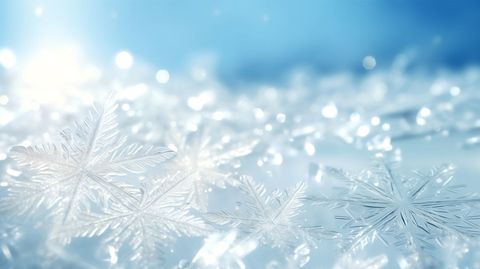 Sparkling macro snowflakes glimmering on soft blue winter bokeh background with icy crystals
