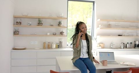 African American Woman Chatting on Phone in Modern Kitchen
