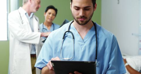 Doctor Uses Digital Tablet During Hospital Shift with Colleagues - Download Free Stock Images Pikwizard.com