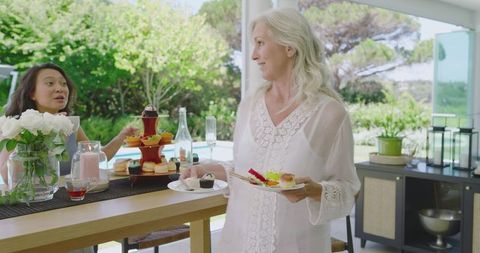 Women enjoying cake celebration on sun-lit patio