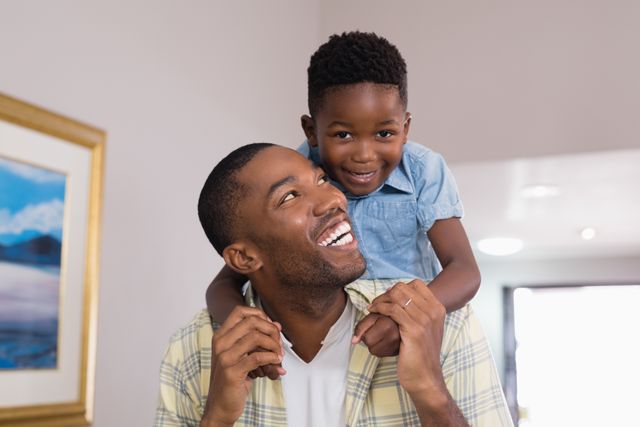 Father and son sharing a joyful moment at home. Perfect for use in family-oriented advertisements, parenting blogs, and articles about fatherhood and family relationships. Highlights themes of love, happiness, and bonding.