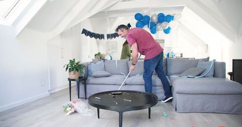 Couple Cleaning Living Room After Festive Birthday Celebration