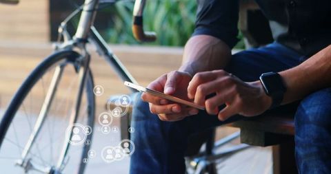Person Navigating Social Media on Smartphone Outdoors Next to Bicycle