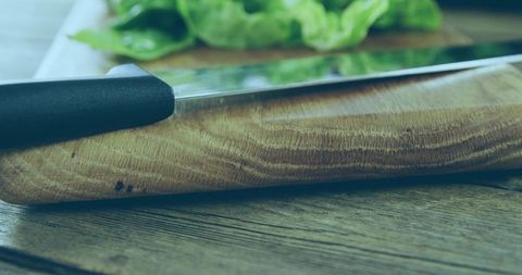 Rustic Wooden Cutting Board Closeup with Knife and Fresh Greens on Table