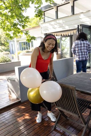 Friends decorating outdoor deck with balloons and bunting